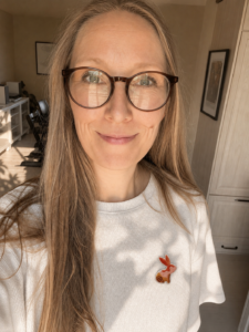 Hvid T-shirt med et påstrygeligt strygemærke formet som en kanin på brystet. Det broderede stofmærke giver T-shirts, sweatshirts og andet tøj et personligt udtryk og kan bruges til at dekorere eller reparere tøj.